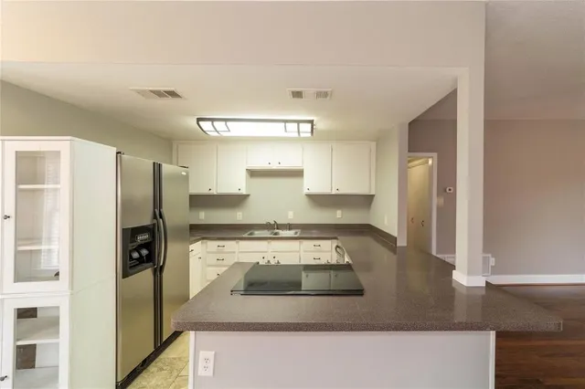 a kitchen with stainless steel appliances granite countertop a refrigerator a stove and a sink with wooden floor