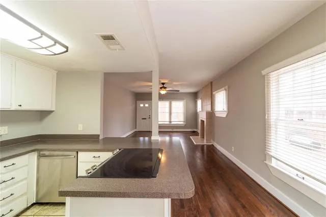 a kitchen with granite countertop a stove a sink and white cabinets with wooden floor next to windows