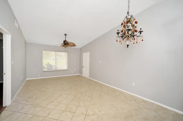 an empty room with windows and chandelier fan