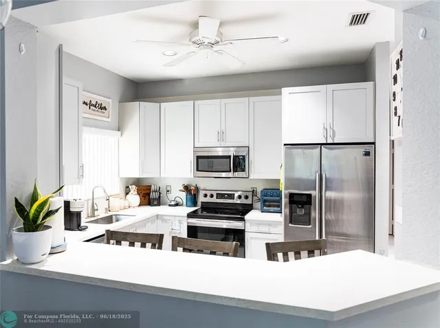 a kitchen with kitchen island a counter top space stainless steel appliances and cabinets