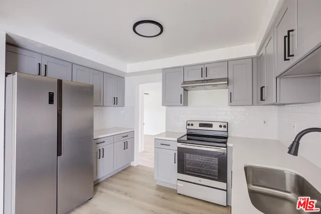 a kitchen with stainless steel appliances a refrigerator stove and white cabinets
