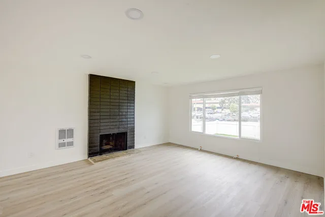 an empty room with fireplace and wooden floor