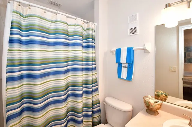 a bathroom with a toilet sink and shower curtain