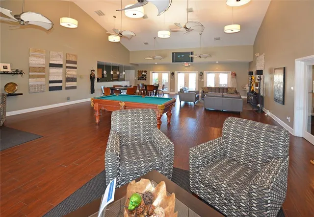 a kitchen with granite countertop a stove a refrigerator a dining table and chairs with wooden floor