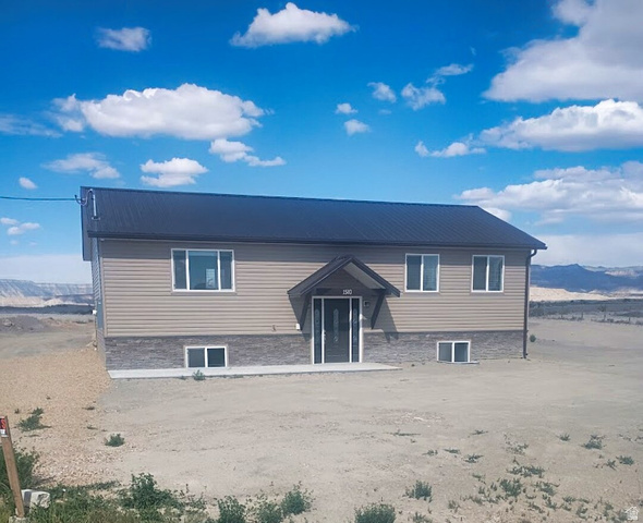 1510 South Lawrence Road Huntington, UT 84528 - Photo 12 of 16 Split-level residence featuring a dark metal roof, tan horizontal siding, and a stone veneer foundation