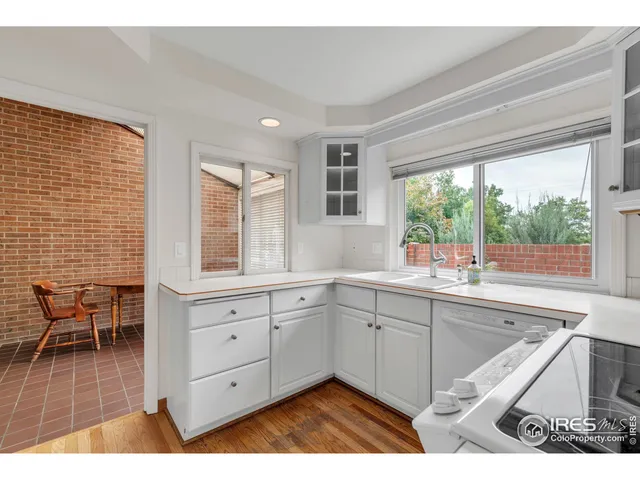 a open kitchen with granite countertop a sink white cabinets and a large window