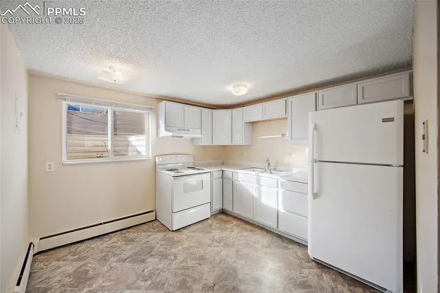 a kitchen with a refrigerator a stove top oven and white cabinets