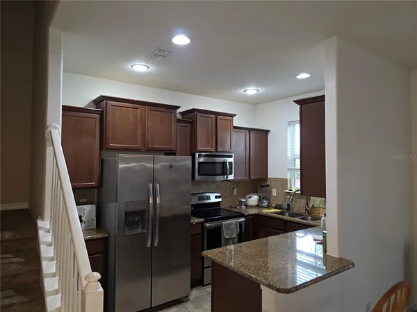 a kitchen with kitchen island granite countertop stainless steel appliances and a refrigerator