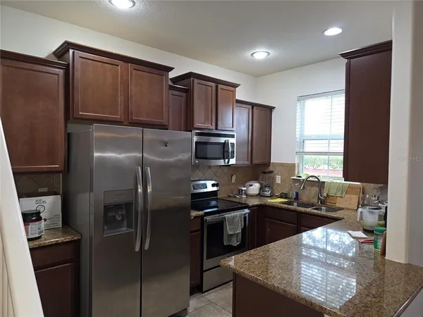 a kitchen with stainless steel appliances granite countertop a sink stove and refrigerator