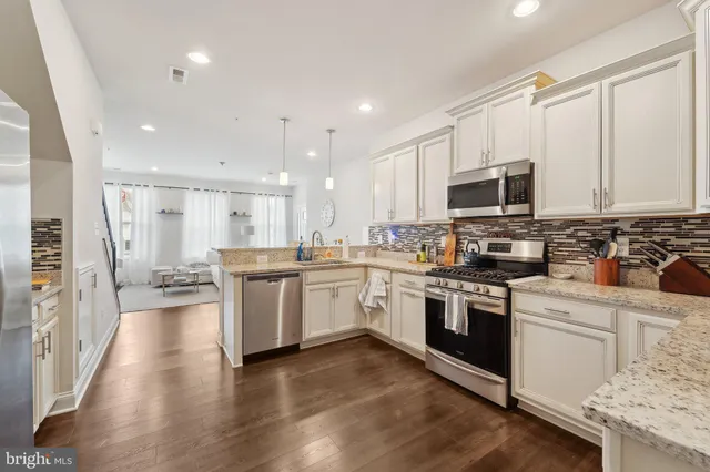 a kitchen with granite countertop appliances cabinets and a wooden floor