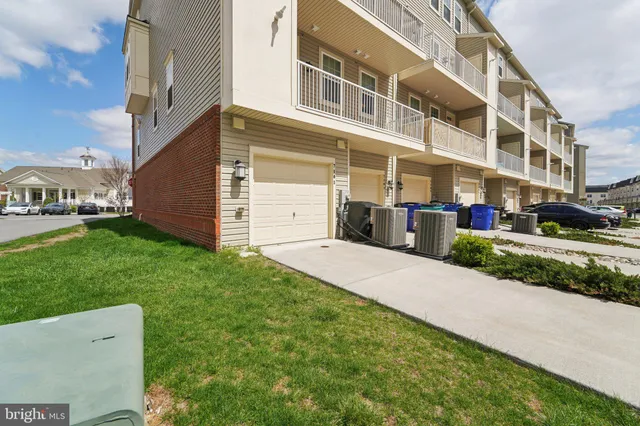 a front view of a building with a yard and plants