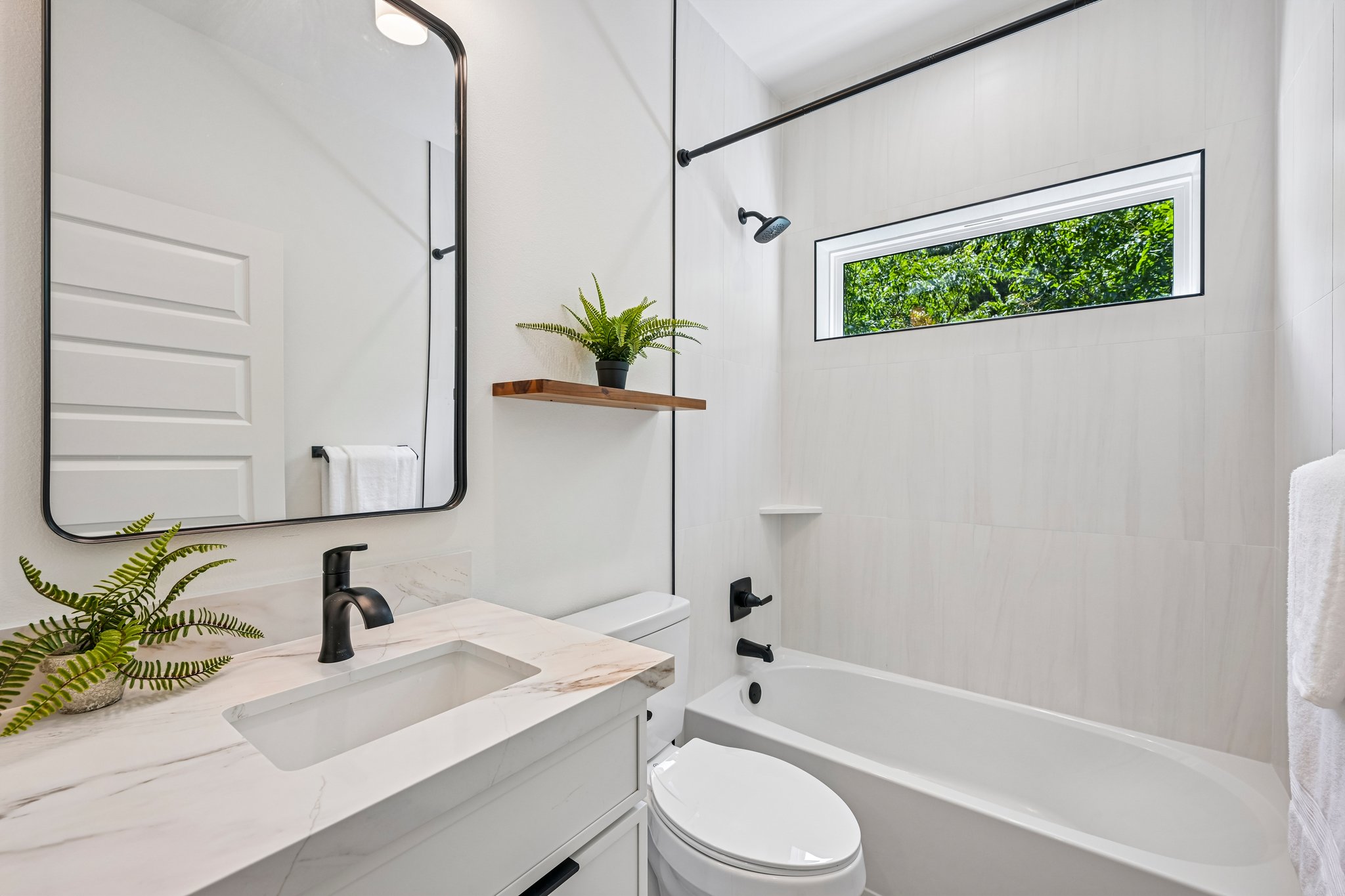 513 West Odell Street, Unit B Austin, TX 78752 - Photo 30 of 38 Sleek vanity with modern fixtures and a window overlooking lush greenery defines this pristine bathroom.