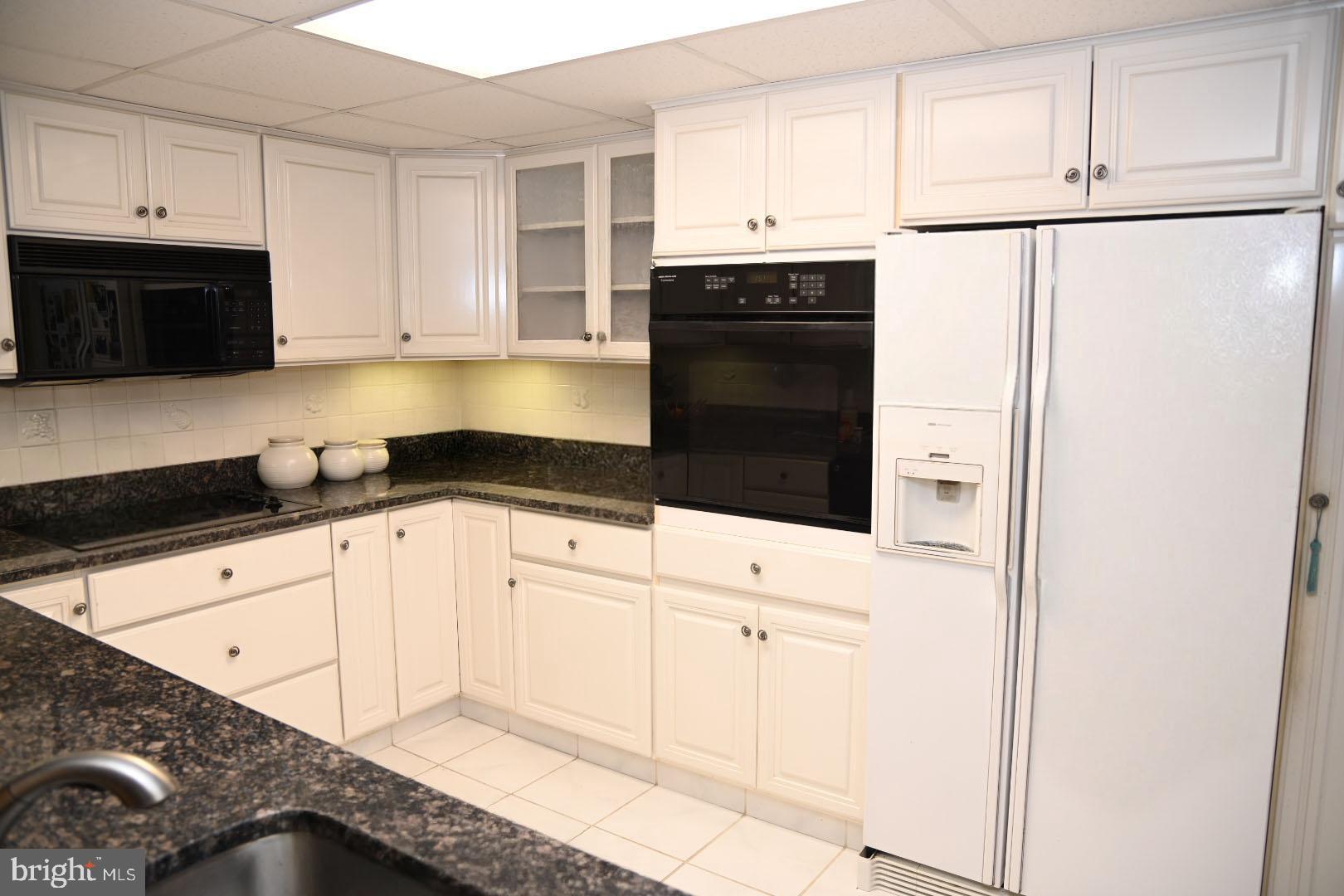 5303 Centennial Station Warminster, PA 18974 - Photo 7 of 60 a kitchen with granite countertop white cabinets and black appliances