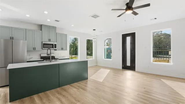 a kitchen with stainless steel appliances granite countertop a refrigerator a sink a stove a microwave and island