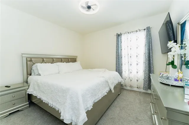 a bedroom with a bed table flat screen tv and window