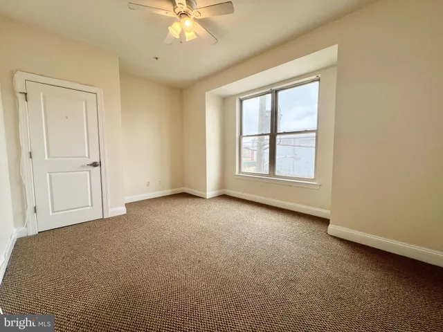 an empty room with windows and fan