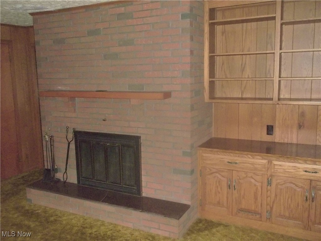 373 May Valley Road Southwest New Philadelphia, OH 44663 - Photo 28 of 38 Unfurnished living room with brick wall, carpet, and a brick fireplace
