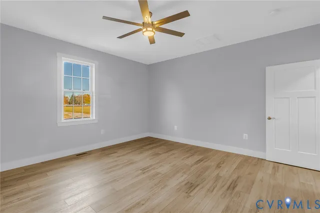 an empty room with wooden floor and windows