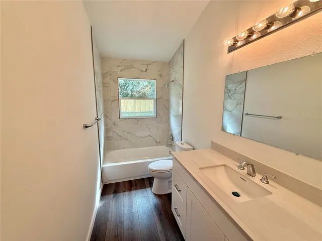 a bathroom with a bathtub sink mirror vanity and toilet