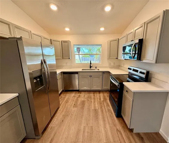 a large kitchen with a sink and refrigerator