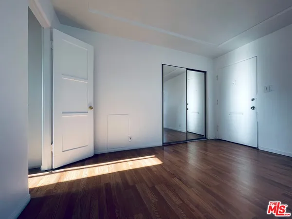 an empty room with wooden floor & windows