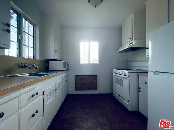 a kitchen with granite countertop white cabinets and white appliances