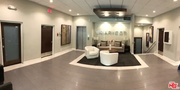 a room with lots of white furniture and chandelier