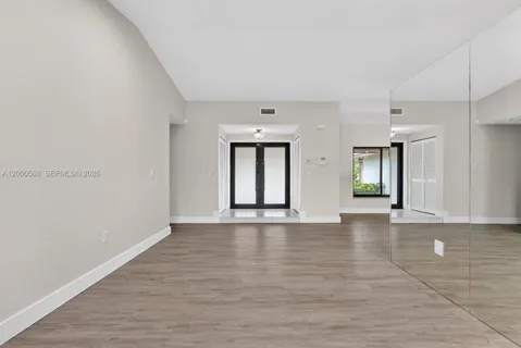 a view of an empty room with window and wooden floor