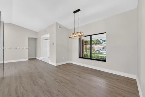 a view of an empty room with wooden floor ceiling fan