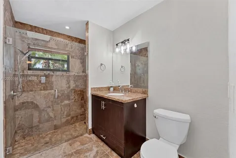 a bathroom with a granite countertop toilet sink and mirror