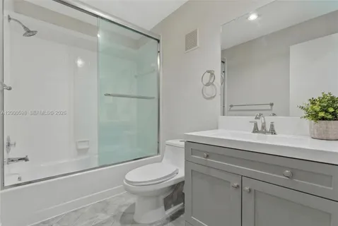 a bathroom with a granite countertop sink a toilet and shower