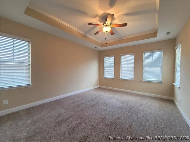 an empty room with chandelier fan and windows