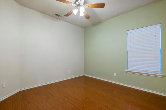 an empty room with a window and a fan