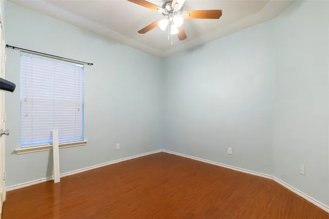 an empty room with chandelier fan and windows