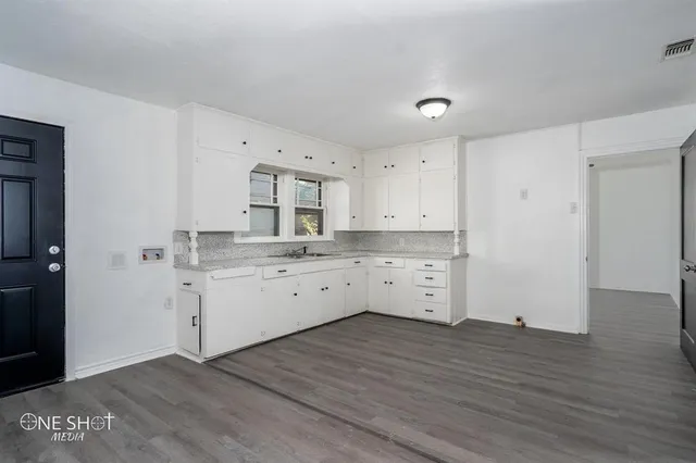 a kitchen with white cabinets and wooden floor