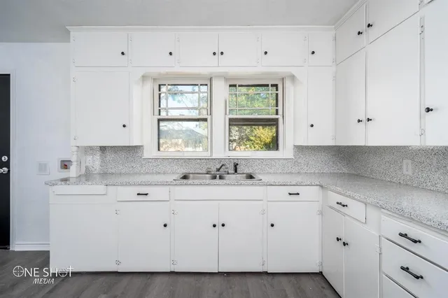 a kitchen with white cabinets and window