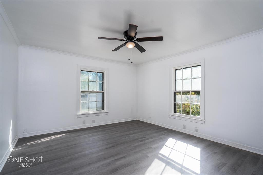 1909 Highland Avenue Abilene, TX 79605 - Photo 10 of 23 an empty room with wooden floor ceiling fan and windows