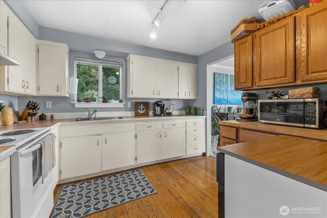 a kitchen with stainless steel appliances granite countertop a stove a sink dishwasher and a microwave oven with white cabinets