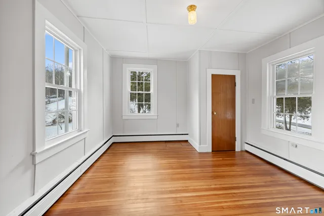 a view of an empty room with a window and wooden floor