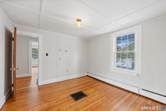 a view of empty room with wooden floor and fan