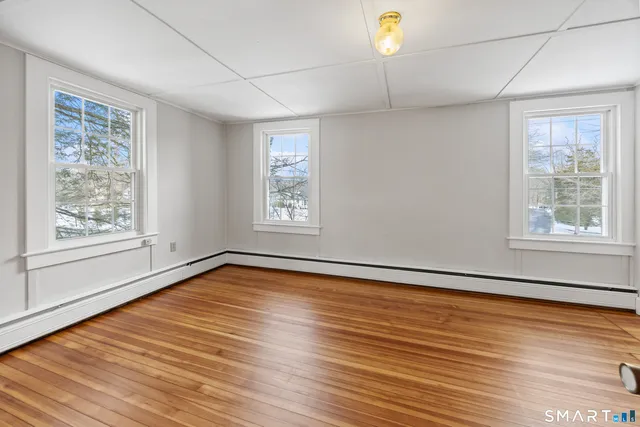 a view of an empty room with a window and wooden floor