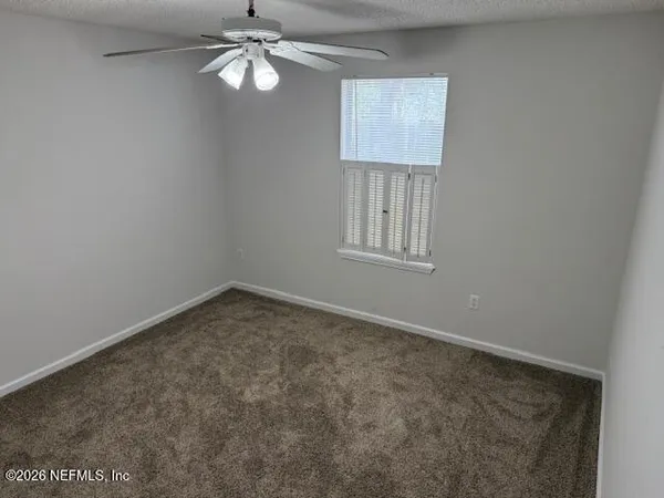 an empty room with windows and fan
