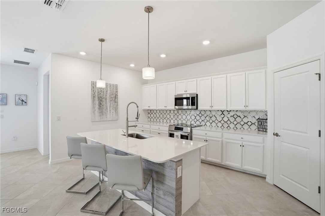 2662 Scarlet Way Naples, FL 34120 - Photo 3 of 47 a kitchen with kitchen island white cabinets and stainless steel appliances