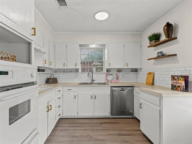 a kitchen with cabinets stainless steel appliances a sink and wooden floor