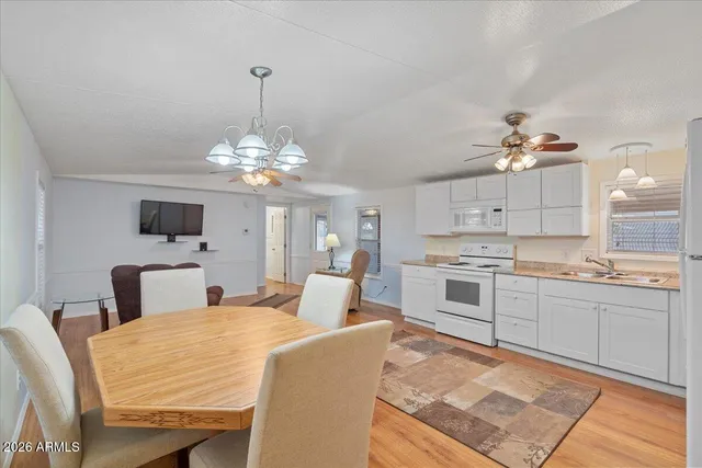 a large white kitchen with a stove a sink a dining table and chairs
