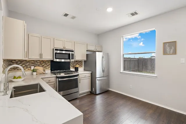 a kitchen with stainless steel appliances a stove a sink and a refrigerator