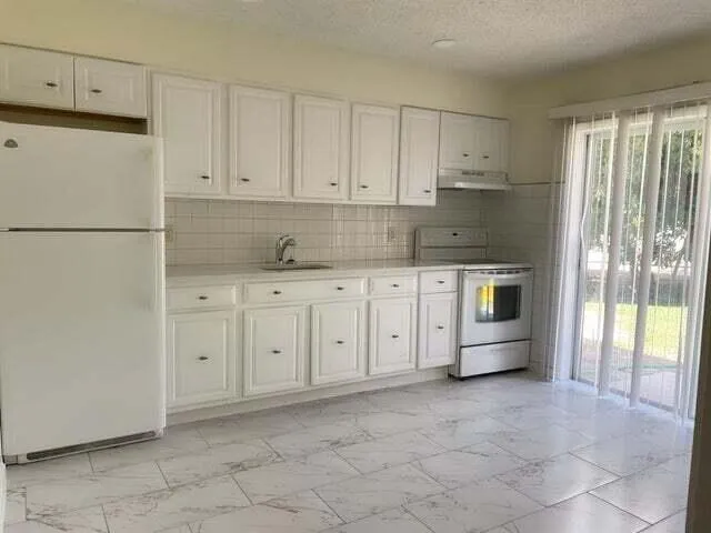 a kitchen with white cabinets and refrigerator