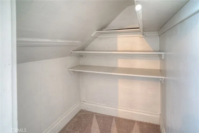 a view of a white house in front of a big yard with plants and large trees