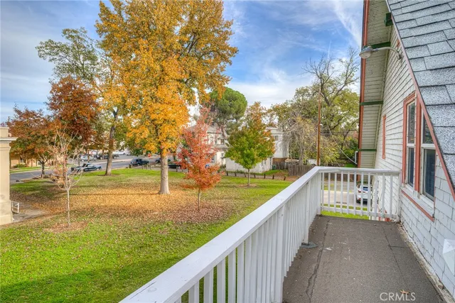 a view of a white house with a big yard and large tree