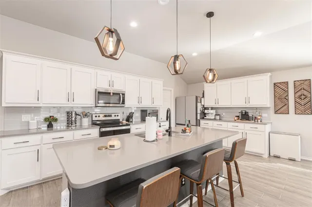 a very nice looking kitchen with a large center island wooden floor stainless steel appliances and cabinets